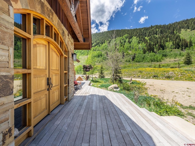 wooden terrace featuring a view of trees and a mountain view