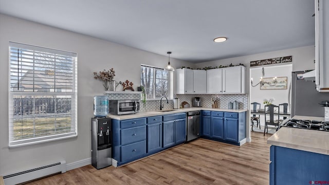 kitchen featuring blue cabinetry, baseboard heating, appliances with stainless steel finishes, a sink, and a chandelier