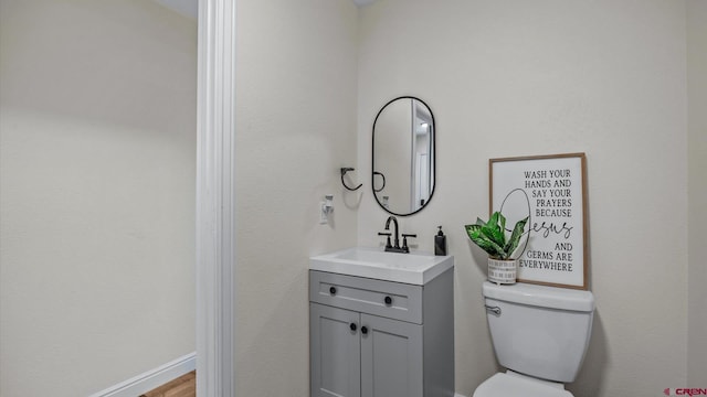 half bath featuring vanity, toilet, and wood finished floors