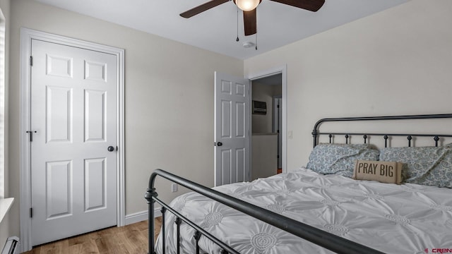 bedroom featuring wood finished floors, a baseboard radiator, and a ceiling fan