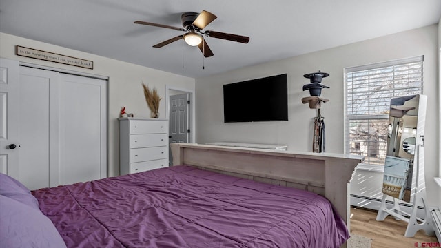 bedroom featuring light wood-type flooring, a closet, a ceiling fan, and baseboard heating