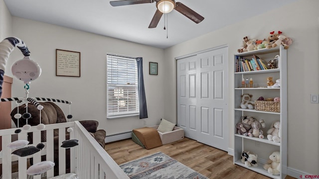 bedroom featuring wood finished floors, a closet, a baseboard radiator, and ceiling fan