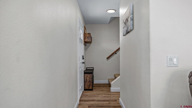 hall with wood finished floors, baseboards, and stairs