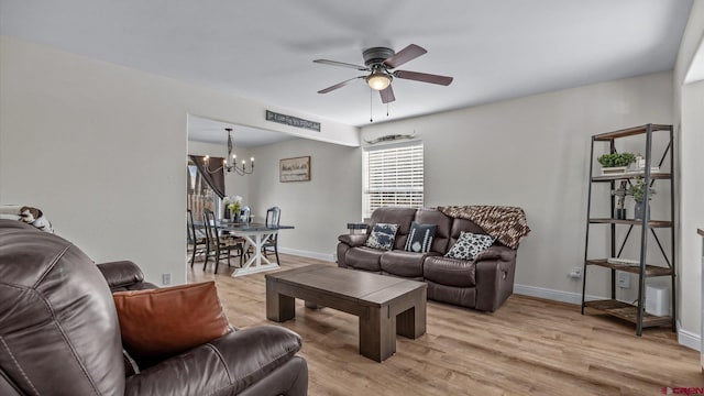 living room featuring a chandelier, a ceiling fan, light wood finished floors, and baseboards