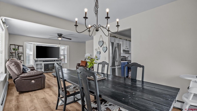 dining room with a ceiling fan, light wood-style floors, baseboard heating, and a chandelier