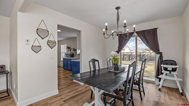 dining space featuring a chandelier, light wood-style flooring, and baseboards