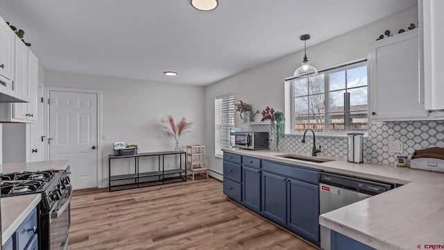 kitchen featuring blue cabinetry, appliances with stainless steel finishes, white cabinetry, a sink, and light countertops