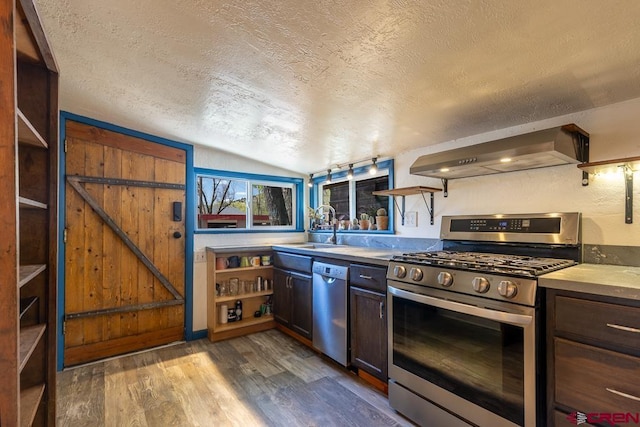 kitchen featuring stainless steel appliances, wall chimney range hood, open shelves, a sink, and a textured ceiling