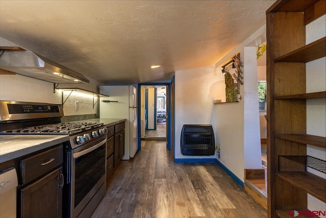 kitchen featuring stainless steel range with gas stovetop, heating unit, wall chimney exhaust hood, dark wood-style flooring, and dishwashing machine