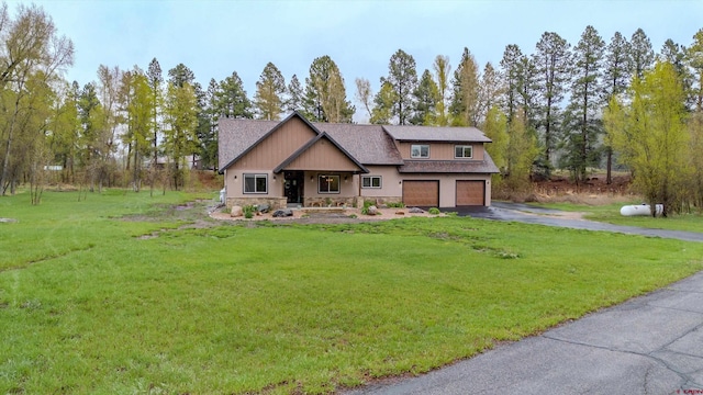craftsman-style home with a garage, driveway, stone siding, and a front yard