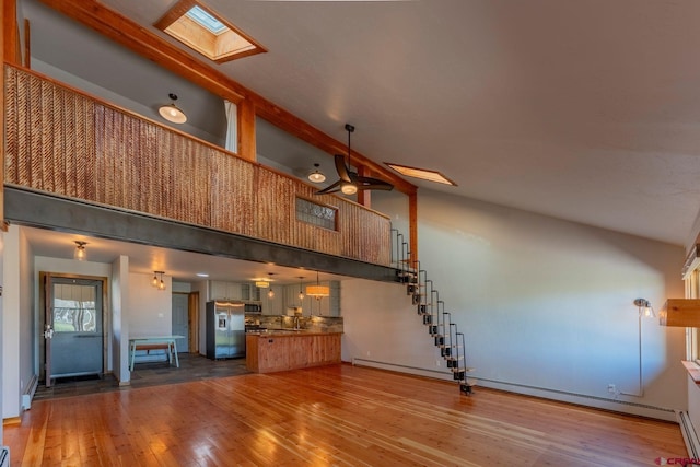 169 Camino Del Rio Unit 8, Gunnison, CO 81230 - unfurnished living room with a skylight, high vaulted ceiling, baseboard heating, hardwood / wood-style flooring, and stairs