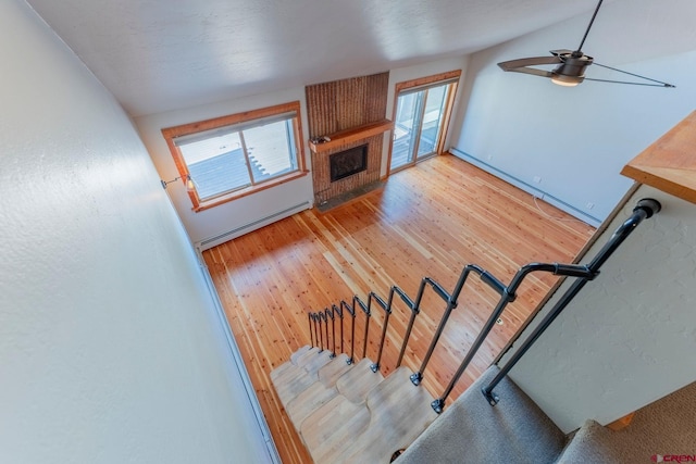 169 Camino Del Rio Unit 8, Gunnison, CO 81230 - stairway featuring a baseboard heating unit, wood finished floors, ceiling fan, a large fireplace, and plenty of natural light
