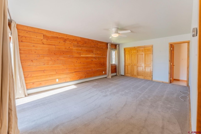 169 Camino Del Rio Unit 8, Gunnison, CO 81230 - unfurnished bedroom featuring carpet floors, wooden walls, a ceiling fan, baseboards, and a baseboard radiator