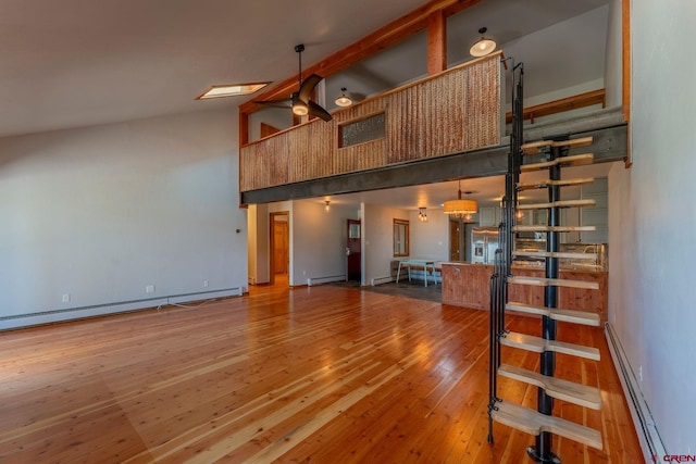 169 Camino Del Rio Unit 8, Gunnison, CO 81230 - unfurnished living room featuring a baseboard radiator, a towering ceiling, hardwood / wood-style floors, baseboard heating, and baseboards