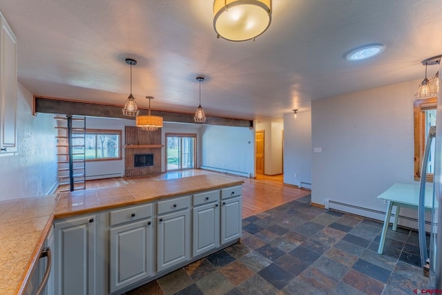 169 Camino Del Rio Unit 8, Gunnison, CO 81230 - kitchen featuring a baseboard radiator, a fireplace, hanging light fixtures, and open floor plan