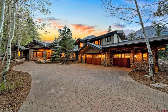 view of front of home with stone siding, decorative driveway, and a garage