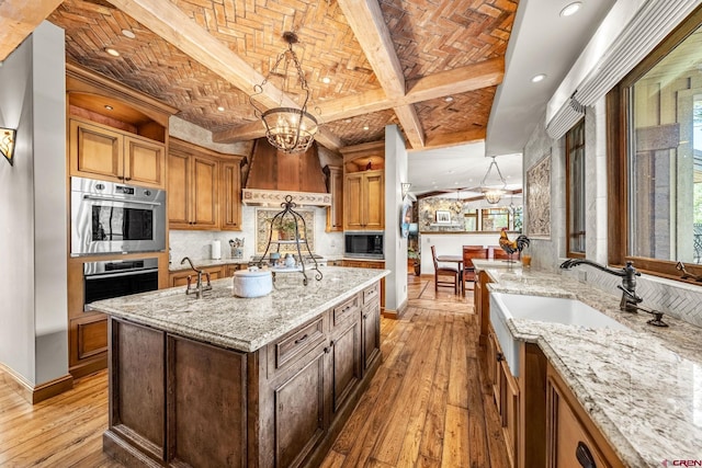 kitchen featuring appliances with stainless steel finishes, a chandelier, baseboards, light wood-style flooring, and beam ceiling