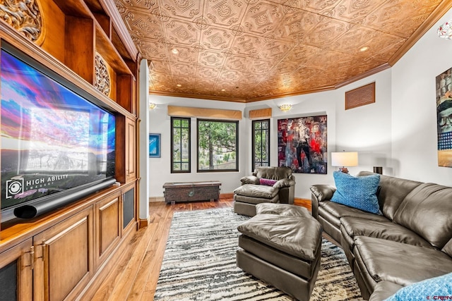living area featuring crown molding, an ornate ceiling, light wood finished floors, and baseboards