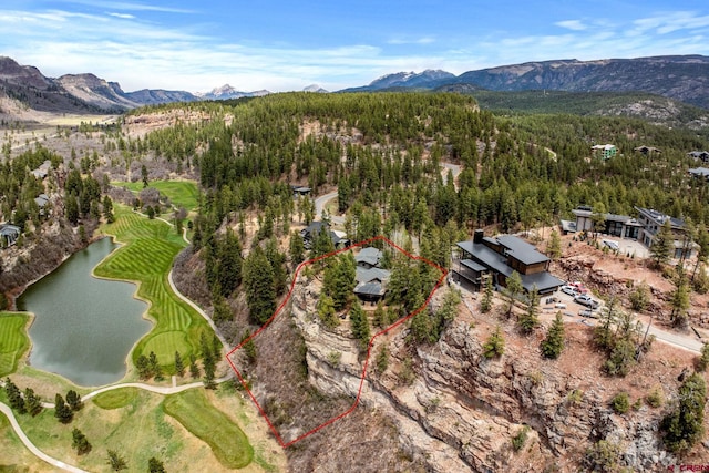 view of property location featuring a water and mountain view, property parcel outlined, a forest, and a golf course