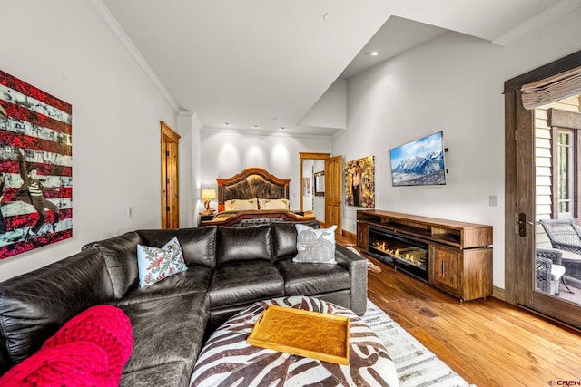 living area with hardwood / wood-style flooring, ornamental molding, a glass covered fireplace, and recessed lighting