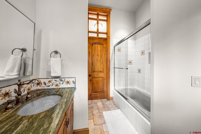 bathroom featuring stone tile flooring, tiled shower / bath combo, and vanity