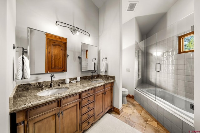 bathroom with toilet, double vanity, lofted ceiling, and baseboards