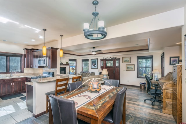 dining space with a raised ceiling, a chandelier, baseboards, a ceiling fan, and recessed lighting