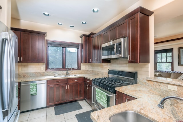 kitchen with appliances with stainless steel finishes, a sink, light stone countertops, light tile patterned floors, and recessed lighting