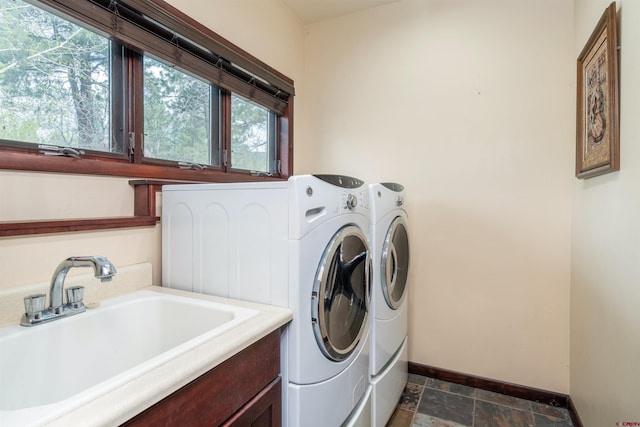 laundry room with washing machine and clothes dryer, baseboards, stone tile flooring, and plenty of natural light