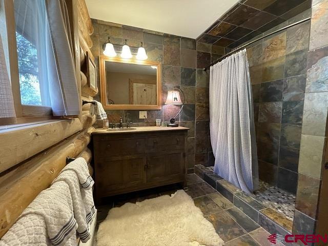 209 Deer Path Ln, Almont, CO 81230 - bathroom featuring a tile shower, vanity, and tile walls