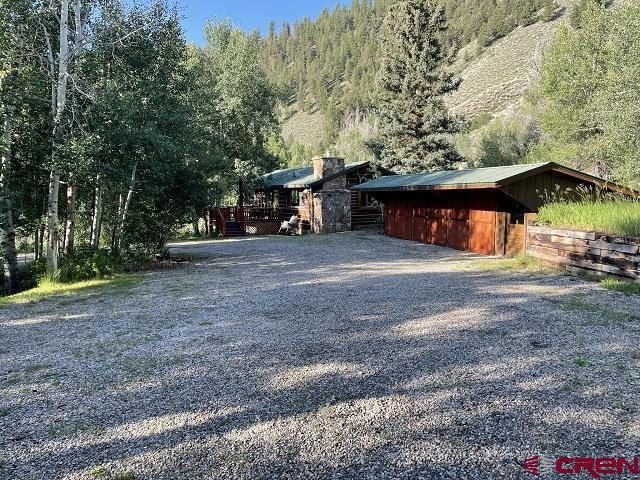 209 Deer Path Ln, Almont, CO 81230 - view of property exterior with a forest view, a chimney, and driveway