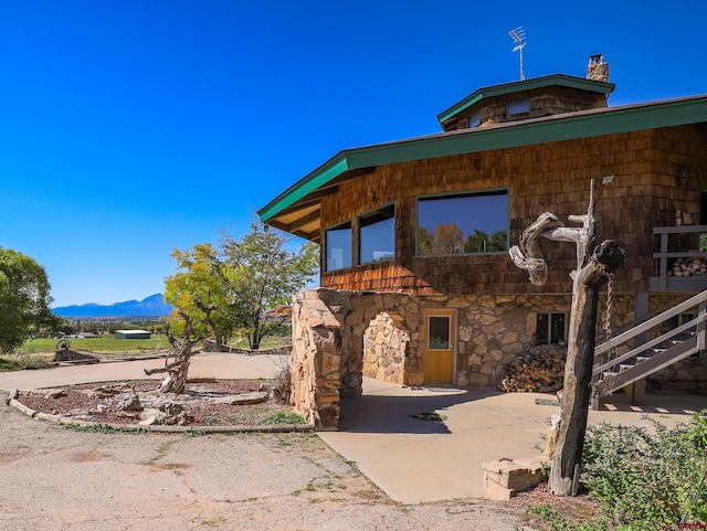 14120 Rd 26, Dolores, CO 81323 - view of home's exterior with a patio, a mountain view, stone siding, and a chimney