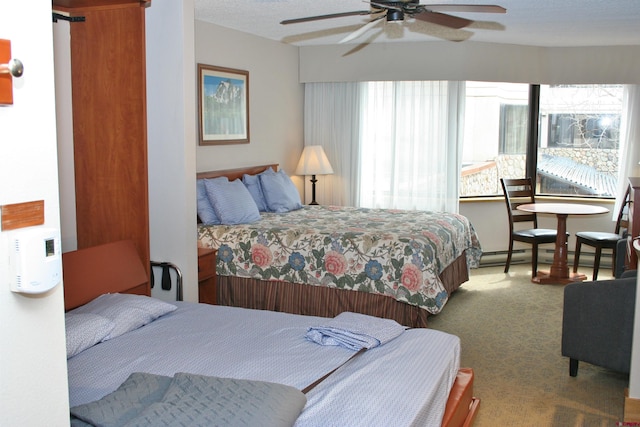 carpeted bedroom featuring a baseboard radiator, multiple windows, ceiling fan, and a textured ceiling