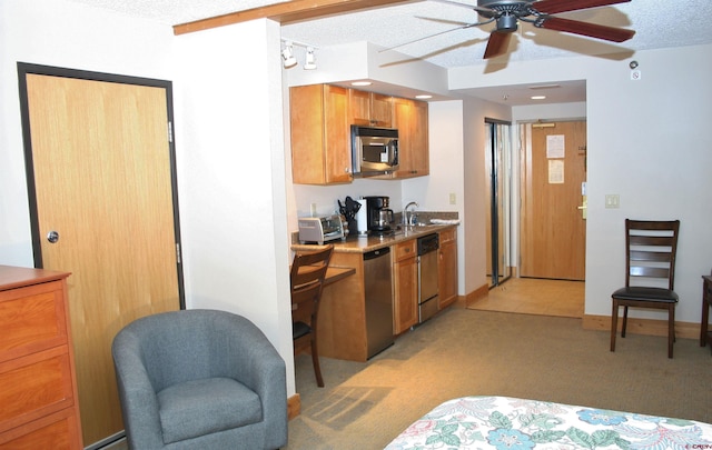 kitchen featuring stainless steel appliances, a ceiling fan, a textured ceiling, light colored carpet, and a sink