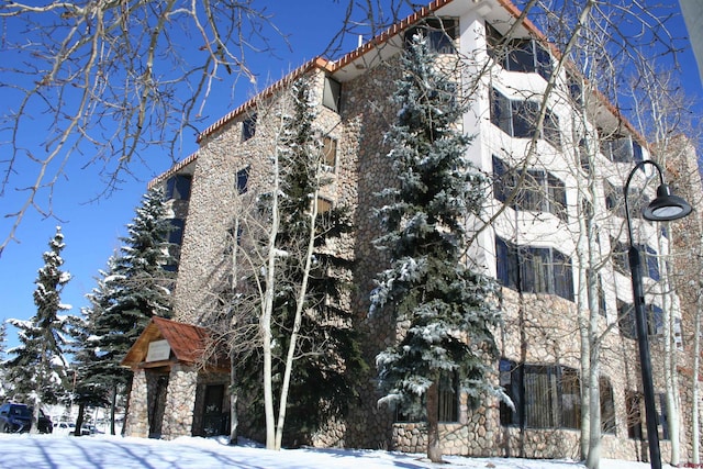 snow covered property featuring a tiled roof