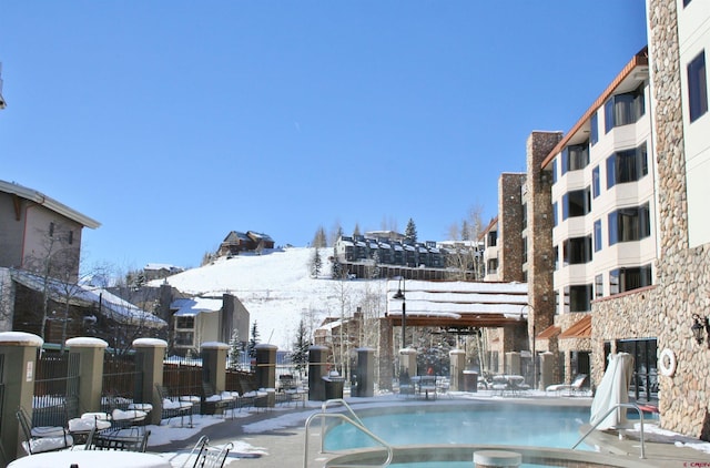 snow covered pool featuring a community pool and fence