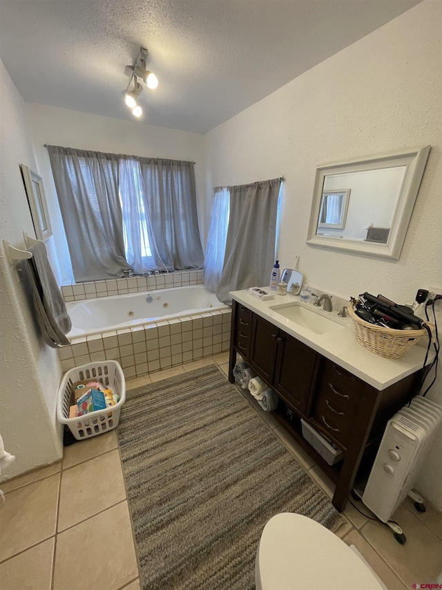 1510 W Sixth St, Alamosa, CO 81101 - bathroom with tile patterned floors, toilet, tiled bath, vanity, and a textured ceiling