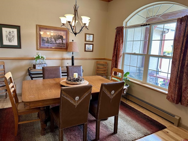 dining room with baseboard heating, wood finished floors, healthy amount of natural light, and a chandelier