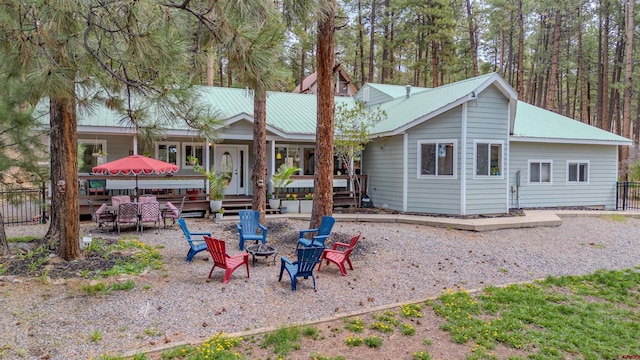 back of property featuring a fire pit, metal roof, and fence
