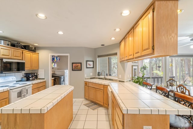 kitchen with white electric stove, a peninsula, tile countertops, recessed lighting, and a sink