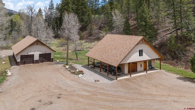 99 River Rd, Durango, CO 81301 - view of front facade with dirt driveway, an outbuilding, a garage, and stucco siding