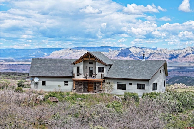 53315 Bull Basin Rd, Mesa, CO 81643 - back of house with a mountain view, stone siding, a shingled roof, and a balcony