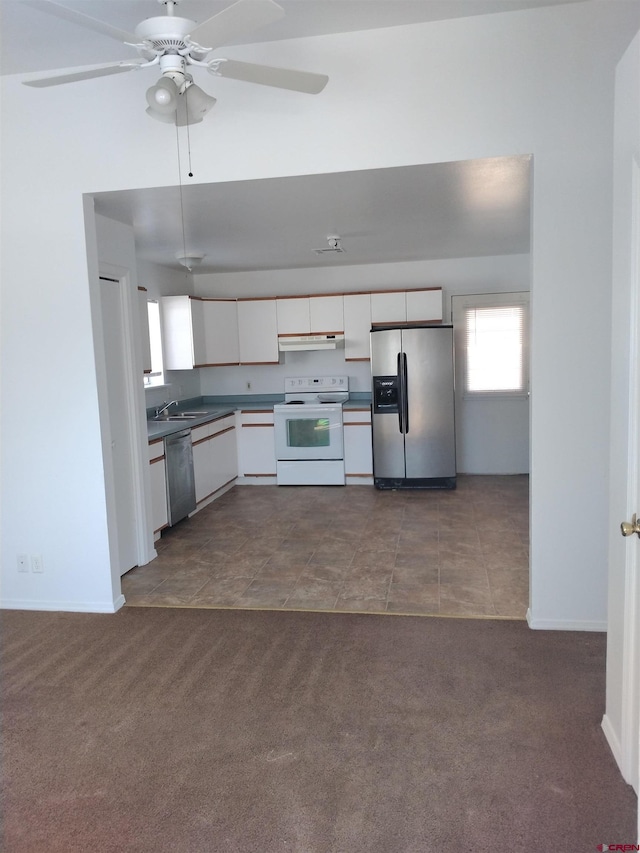 240 S Madison St, Cortez, CO 81321 - kitchen with stainless steel appliances, under cabinet range hood, dark countertops, white cabinets, and dark carpet