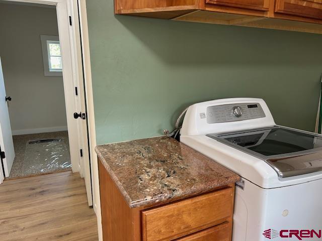 1414 Bluff St, Delta, CO 81416 - clothes washing area featuring washer / clothes dryer, cabinet space, light wood-type flooring, and baseboards
