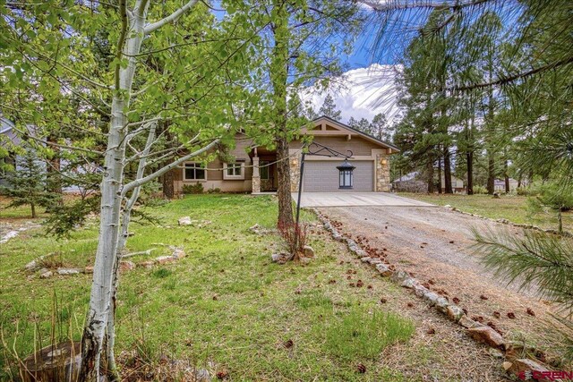 39 Garnet Ct, Pagosa Springs, CO 81147 - view of front of house featuring driveway, an attached garage, a front lawn, and stone siding