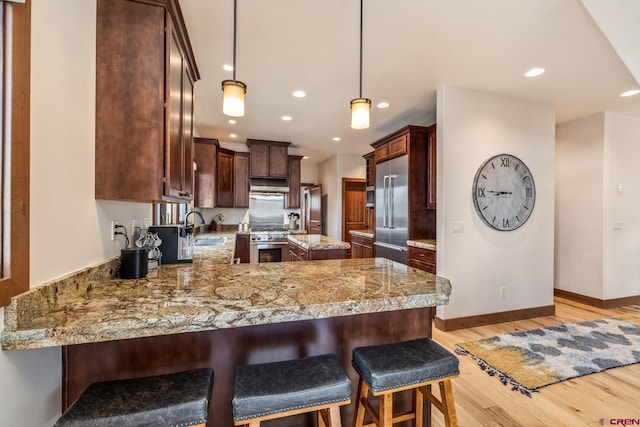 32 Cinnamon Mountain Rd, Mount Crested Butte, CO 81225 - kitchen with high quality appliances, a sink, a peninsula, light wood-style floors, and baseboards