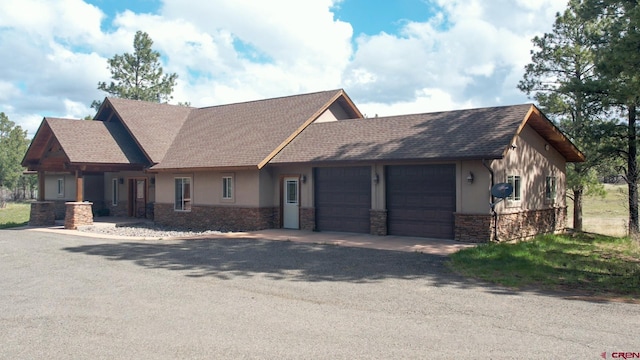 584 Oren Rd, Pagosa Springs, CO 81147 - view of front facade with stone siding, a garage, stucco siding, roof with shingles, and driveway