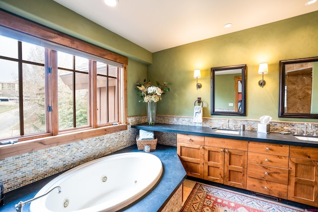full bathroom featuring healthy amount of natural light, a tub with jets, double vanity, and recessed lighting