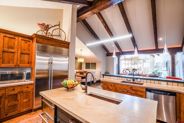kitchen featuring appliances with stainless steel finishes, open floor plan, brown cabinetry, and a sink
