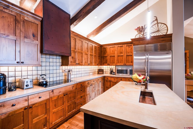 kitchen featuring stainless steel appliances, light countertops, tasteful backsplash, light wood-style flooring, and brown cabinets